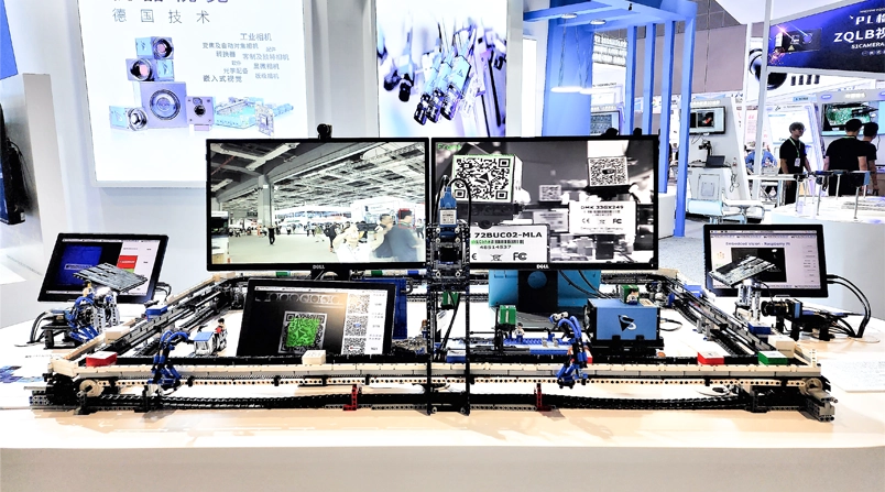 主展桌展示一个正在运作的玩具工厂，其中包含The Imaging Source工业相机产品系列的各式相机: 变焦相机，FPD-Link™ III相机模组 (嵌入式视觉)，33系列和37系列。
